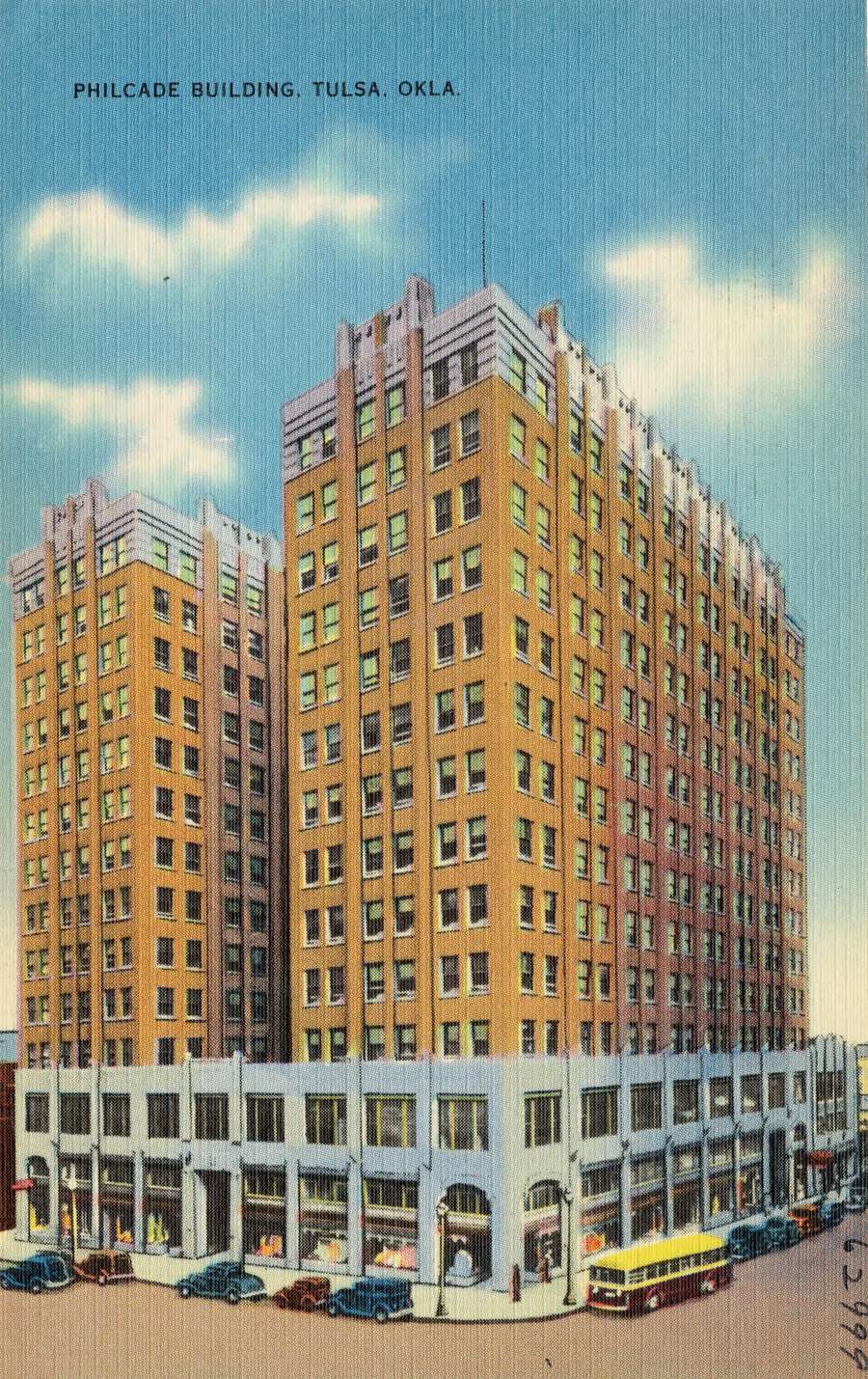 Colour postcard of the Philcade Building, a tall brick office block in Tulsa, with 1930s cars and a bus on the street